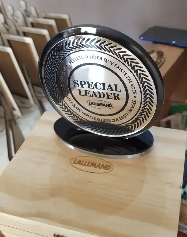 Peça circular preta e dourada com inscrição Special Leader sobre base