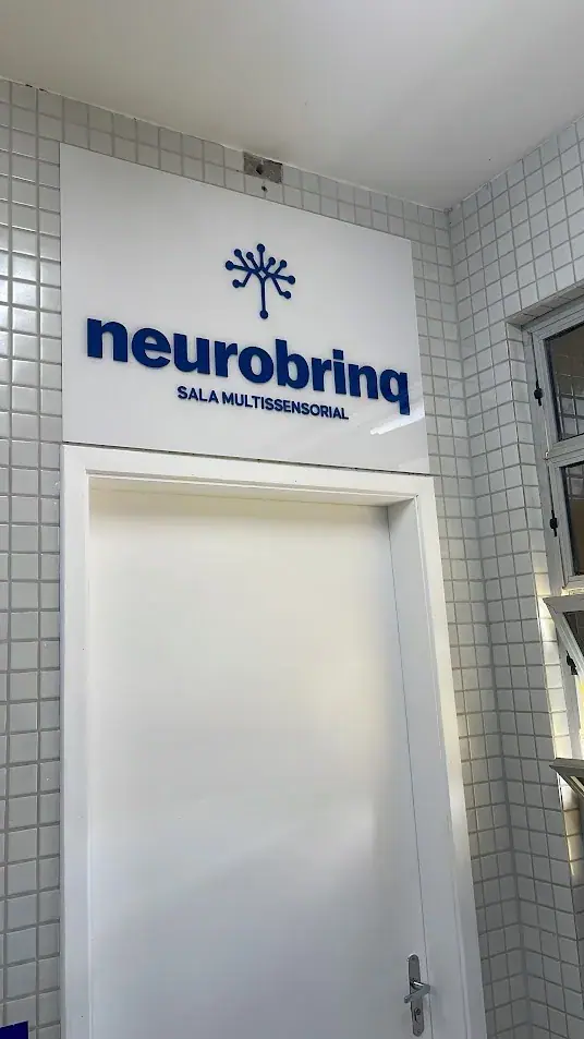 Placa branca com logotipo azul instalada acima de uma porta