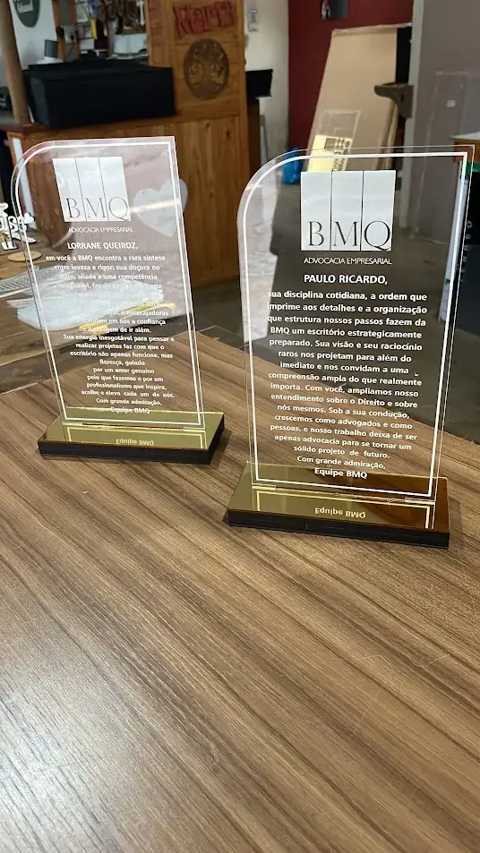 Duas placas transparentes verticais com texto gravado e bases douradas